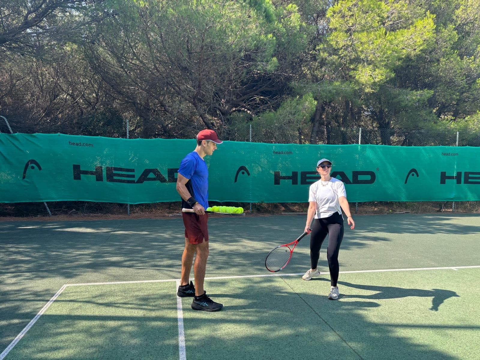 Séance de coaching sur court extérieur, banderole HEAD en fond